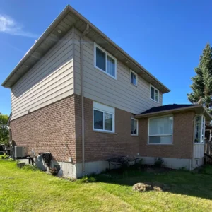 Before picture of a red brick and beige siding house